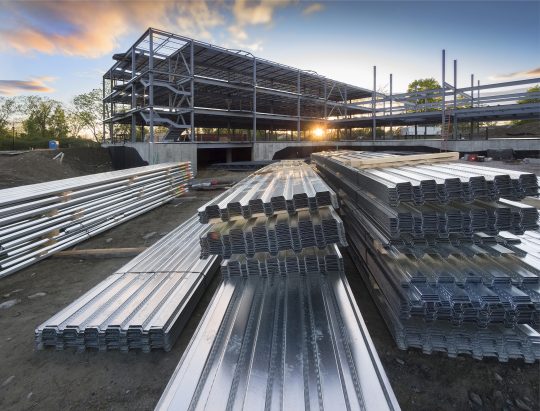 Construction site with steel flooring in front of a  partially erected building at sunset